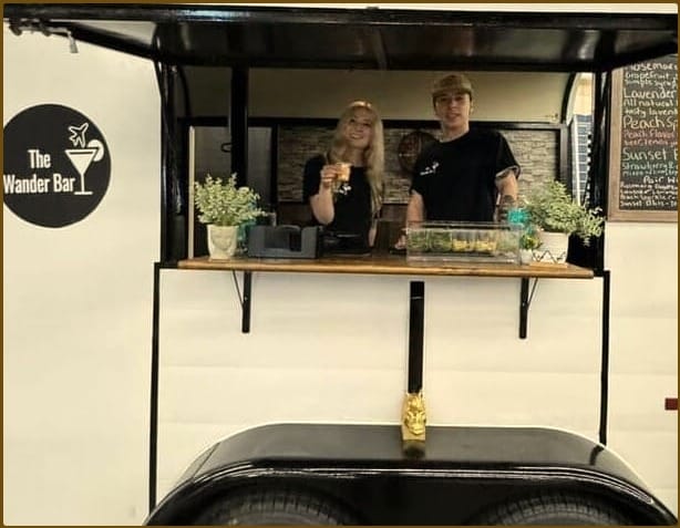 The Wander Bar's renovated vintage horse trailer set up as a mobile bar at an outdoor New Hampshire event